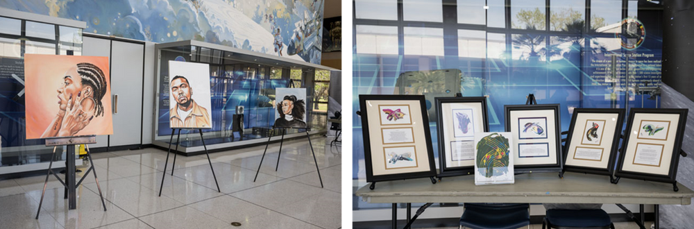 Art is displayed on easels and in frames on a table during an exhibition.